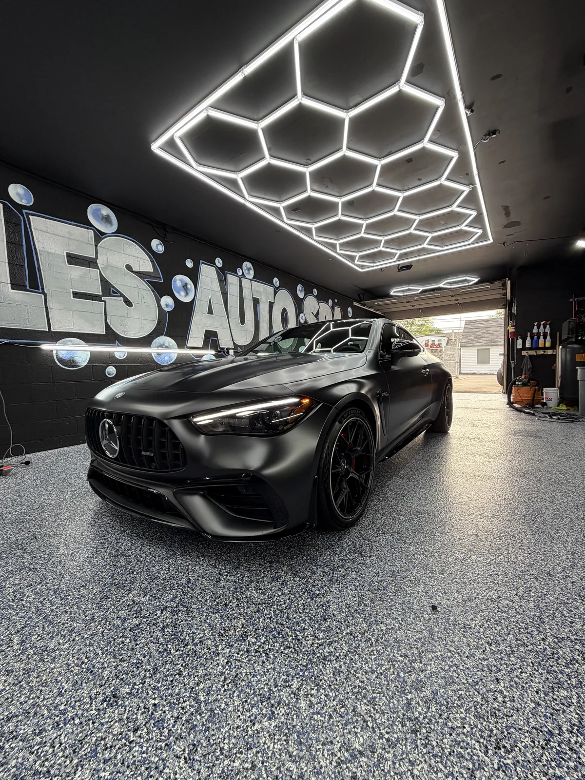 Black Mercedes-AMG under the hexagonal lights in the studio